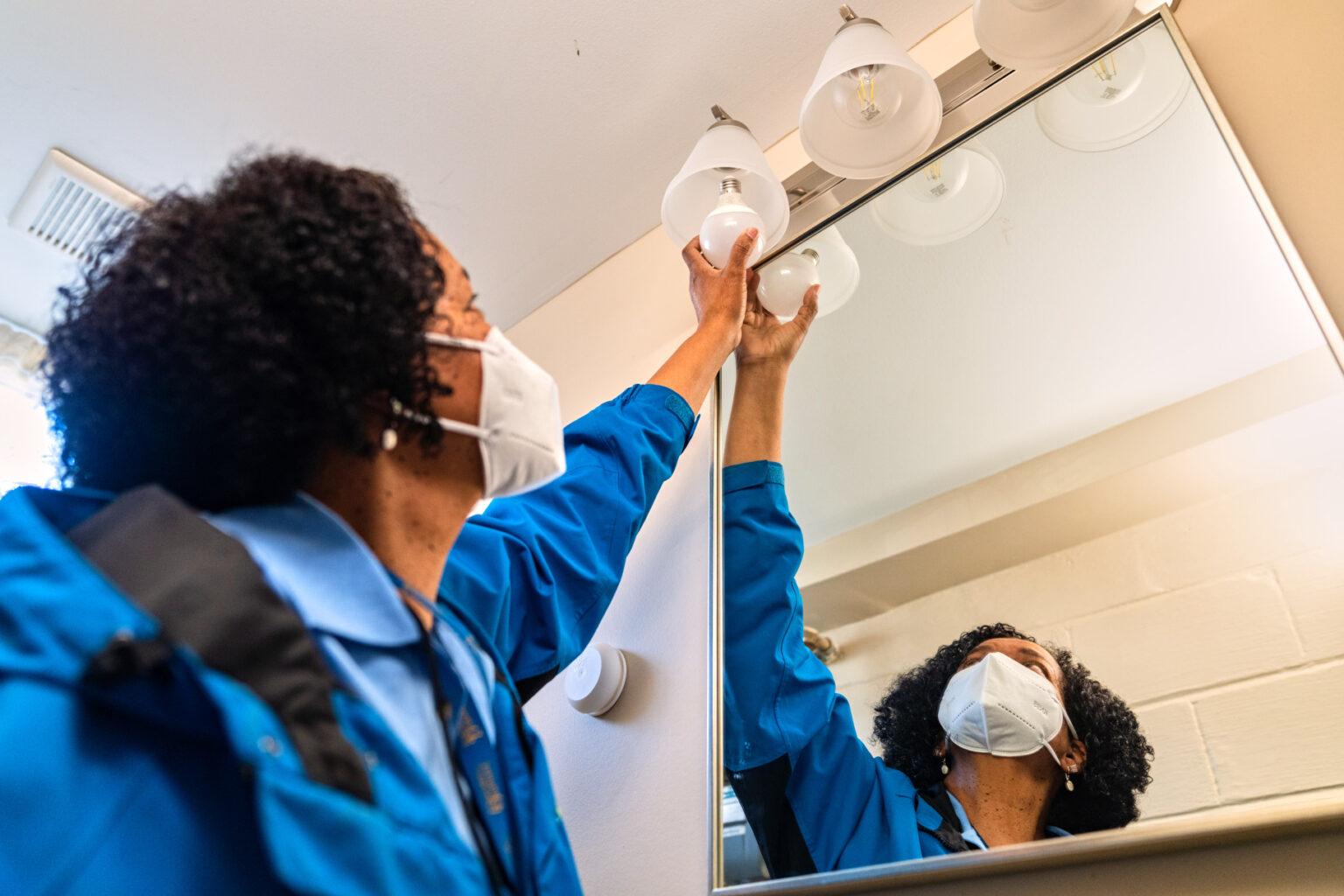 Civic Works staff member replacing inefficient light bulbs with LED light bulbs