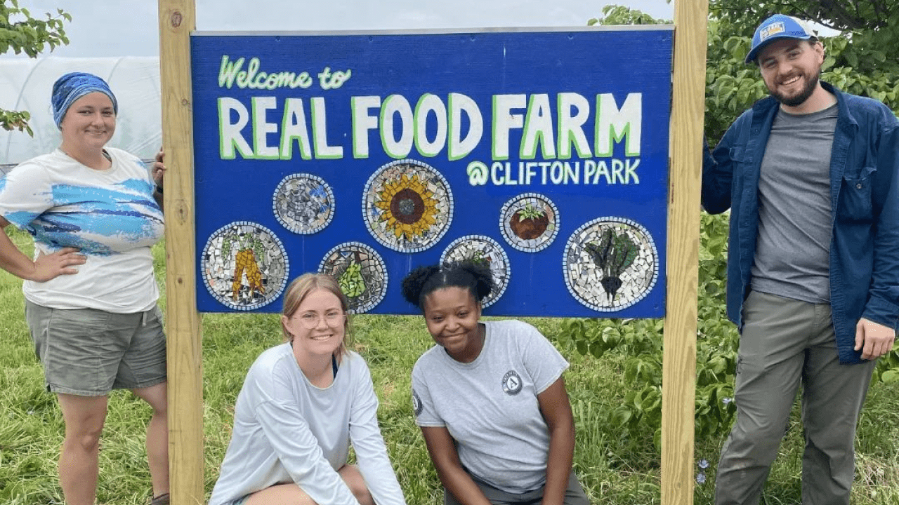 Civic works employees standing in front of real food farm sign